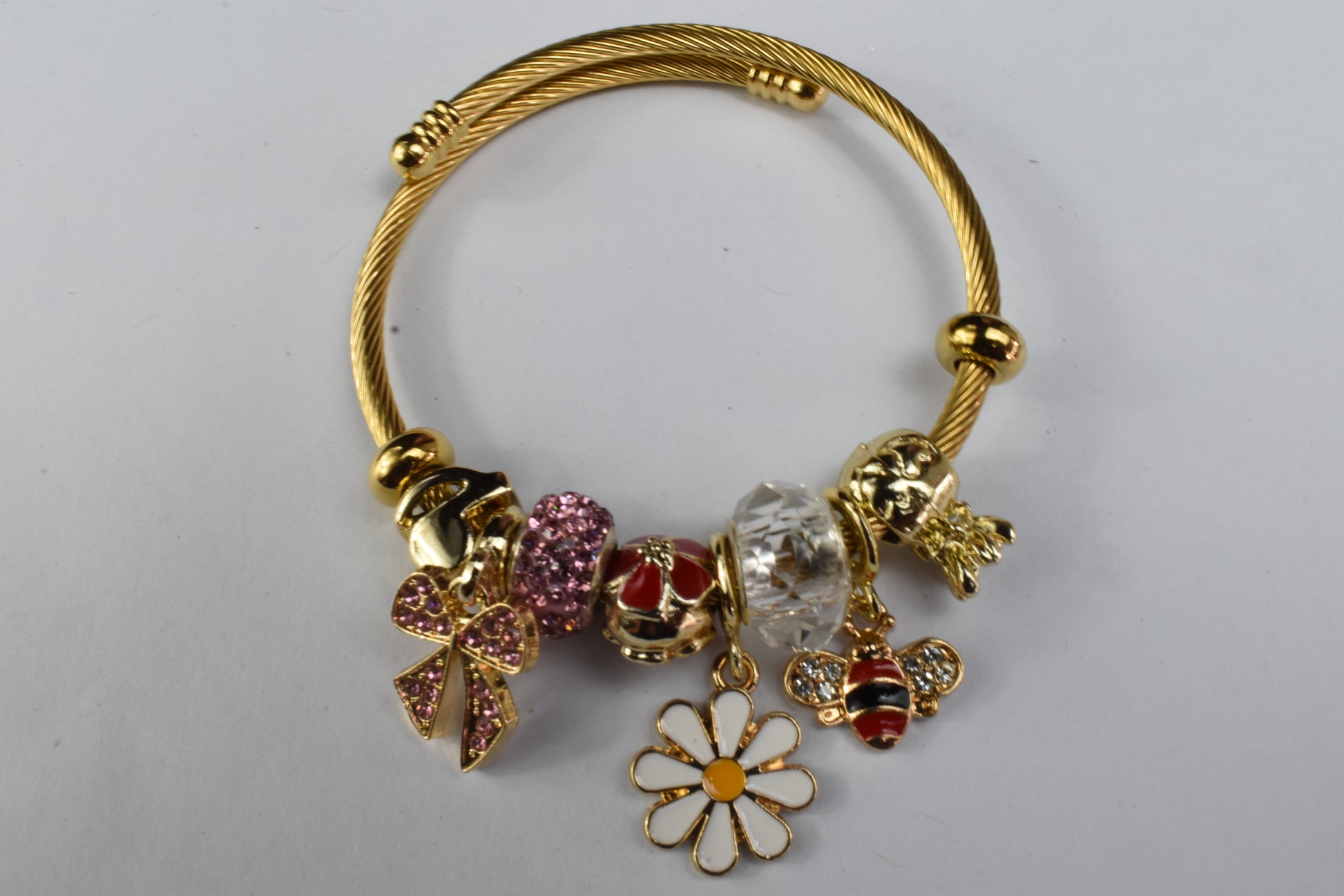 Gold bracelet with daisy, bee, and pink bow charms