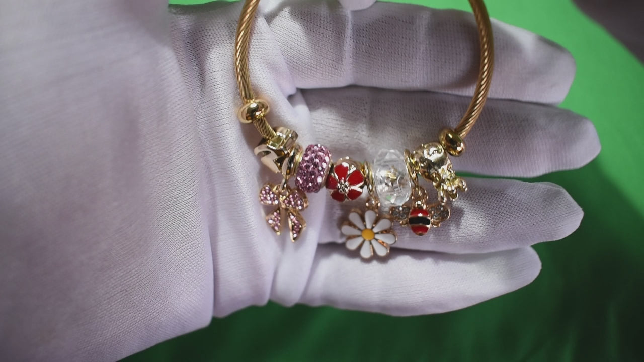 Gold bracelet with daisy, bee, and pink bow charms